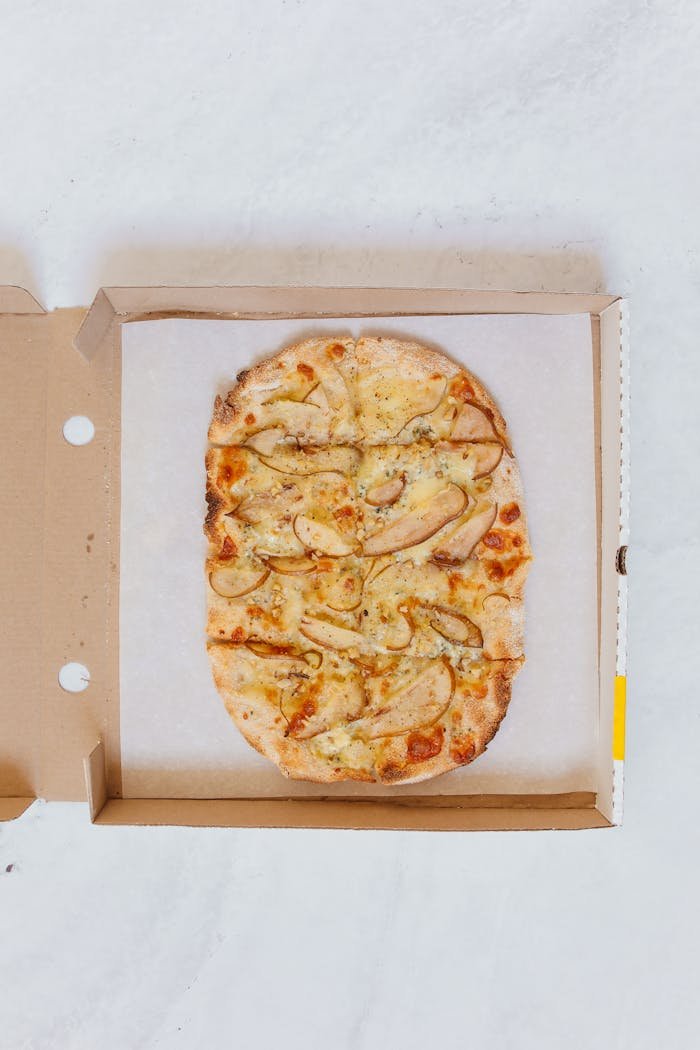 Delicious Italian flatbread pizza presented in an open cardboard box, shot from above.